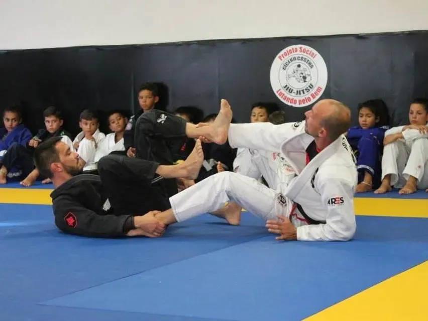 Baptiste Landais et Yohan Bonnet font une démonstration au sol devant un groupe d’enfants assis au bord du tatami